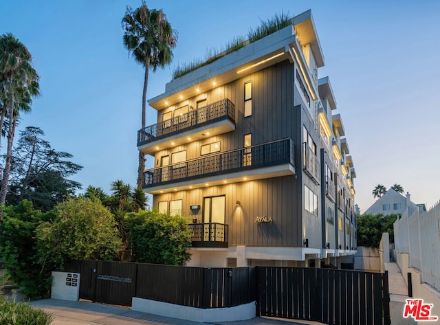 back house at dusk featuring a balcony