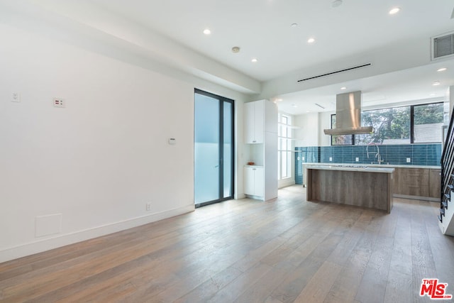 kitchen featuring a kitchen island, island range hood, tasteful backsplash, sink, and light hardwood / wood-style flooring