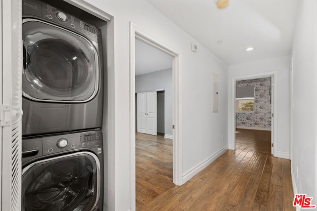 laundry room featuring stacked washer / dryer, hardwood / wood-style flooring, and electric panel