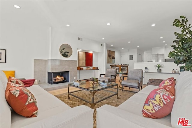 living room with a high end fireplace and light wood-type flooring