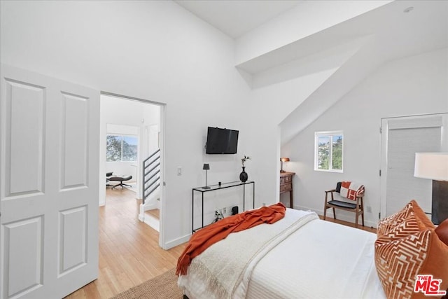 bedroom with multiple windows, light hardwood / wood-style flooring, and lofted ceiling