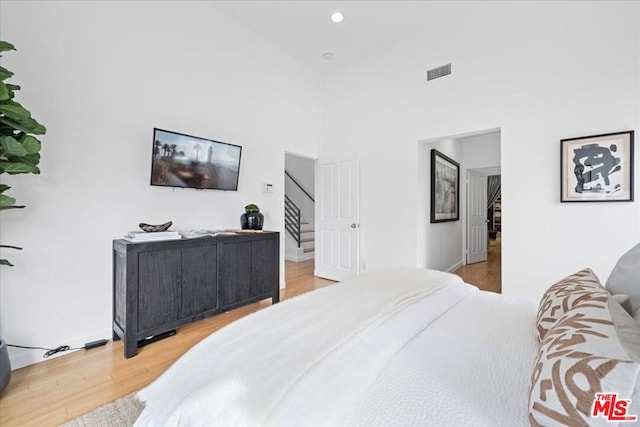 bedroom with a high ceiling and light wood-type flooring