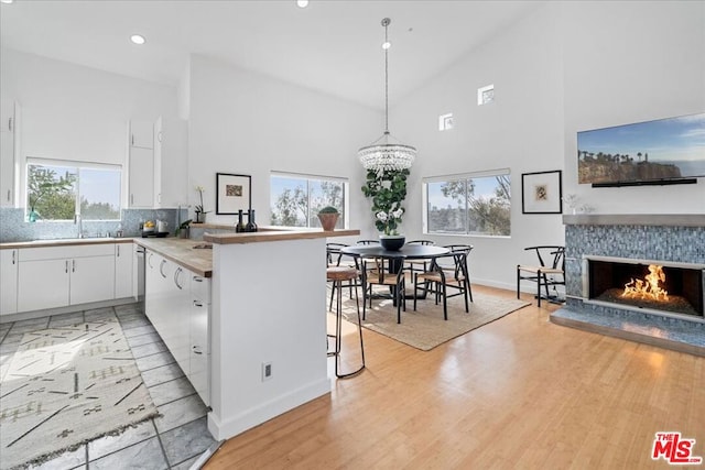 kitchen with a breakfast bar area, white cabinetry, decorative light fixtures, kitchen peninsula, and a fireplace