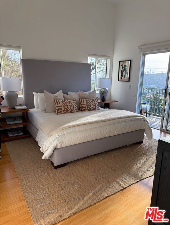 bedroom with access to exterior and wood-type flooring