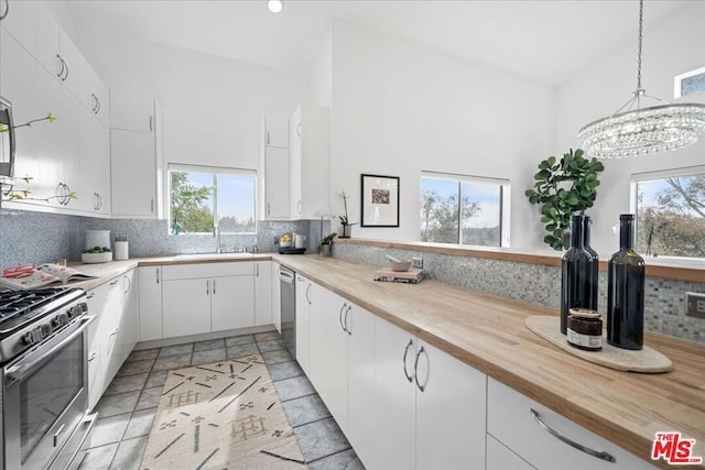 kitchen with sink, white cabinetry, hanging light fixtures, stainless steel appliances, and decorative backsplash