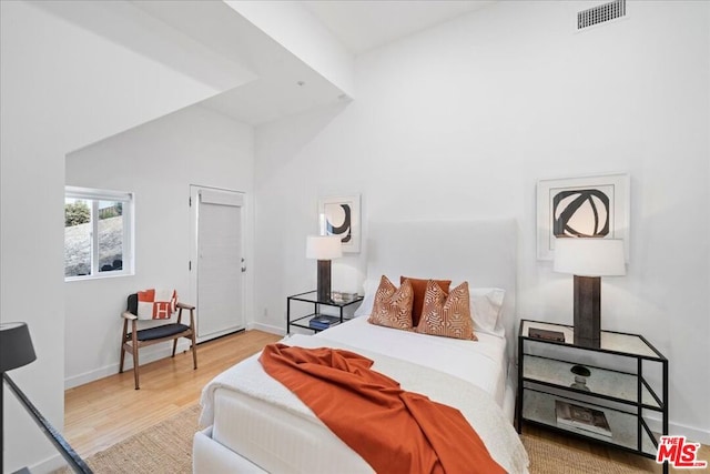 bedroom featuring hardwood / wood-style flooring, vaulted ceiling, and a wood stove