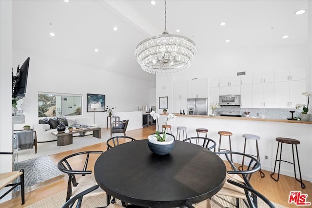 dining room featuring beamed ceiling, high vaulted ceiling, light hardwood / wood-style floors, and a notable chandelier