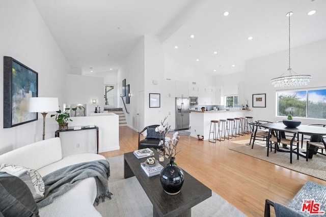 living room featuring a notable chandelier, beam ceiling, high vaulted ceiling, and light wood-type flooring