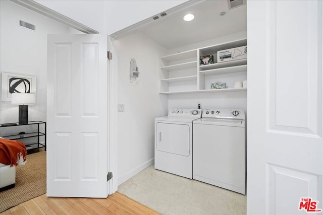 laundry room with independent washer and dryer and light hardwood / wood-style flooring