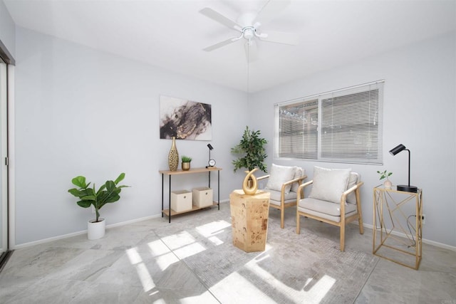 sitting room with a ceiling fan and baseboards