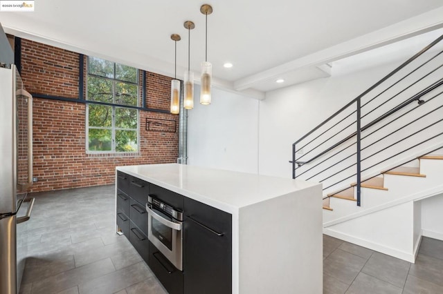 kitchen featuring a kitchen island, brick wall, decorative light fixtures, and stainless steel appliances