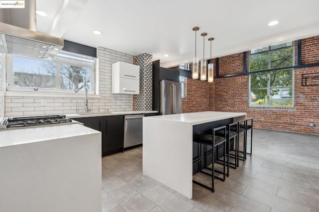 kitchen with pendant lighting, a breakfast bar, appliances with stainless steel finishes, white cabinets, and a kitchen island