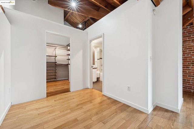 unfurnished bedroom featuring light hardwood / wood-style floors, vaulted ceiling with beams, wooden ceiling, and a closet