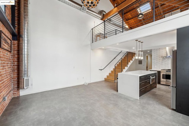 unfurnished living room with brick wall and a high ceiling