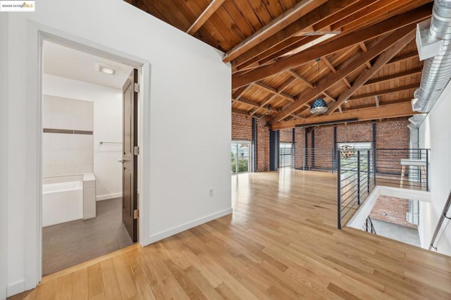 hall featuring lofted ceiling with beams, brick wall, wood ceiling, and light hardwood / wood-style floors