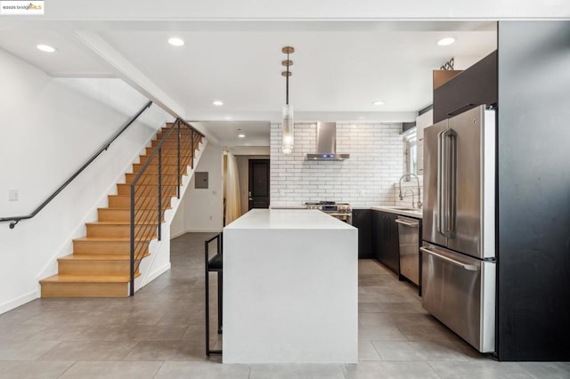 kitchen with sink, wall chimney range hood, hanging light fixtures, a center island, and high end appliances