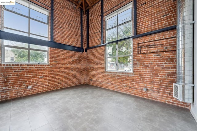 spare room with a towering ceiling and brick wall