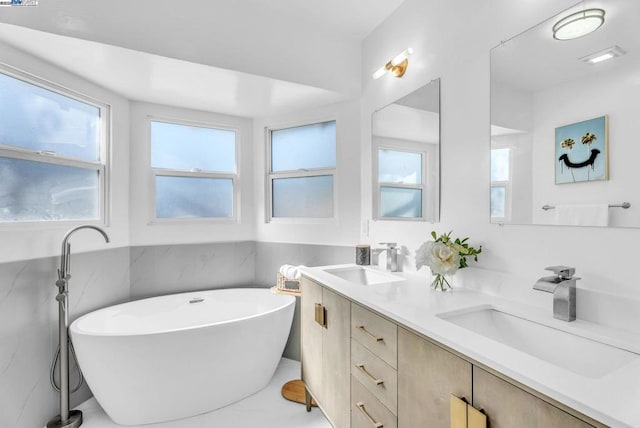 bathroom with vanity, plenty of natural light, tile walls, and a tub to relax in