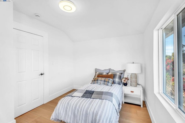 bedroom with lofted ceiling and light wood-type flooring