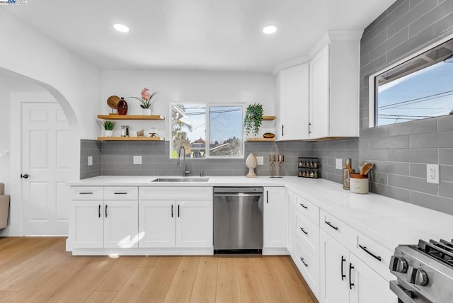 kitchen with stainless steel appliances, sink, white cabinets, and backsplash