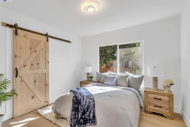 bedroom featuring light hardwood / wood-style flooring and a barn door