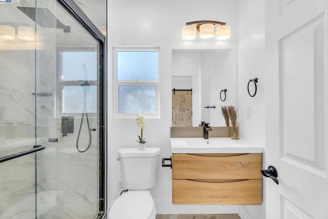 bathroom featuring a shower with door, vanity, and toilet