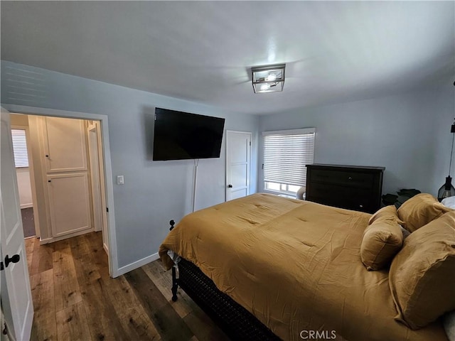 bedroom with multiple windows and dark hardwood / wood-style floors