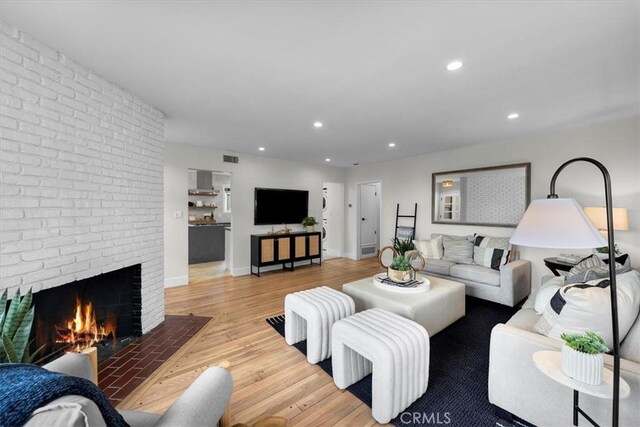 living room with a brick fireplace and light hardwood / wood-style flooring