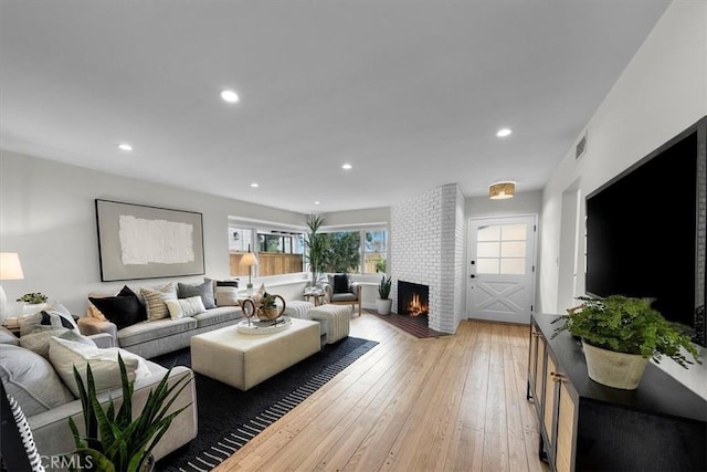 living room with light hardwood / wood-style floors and a brick fireplace