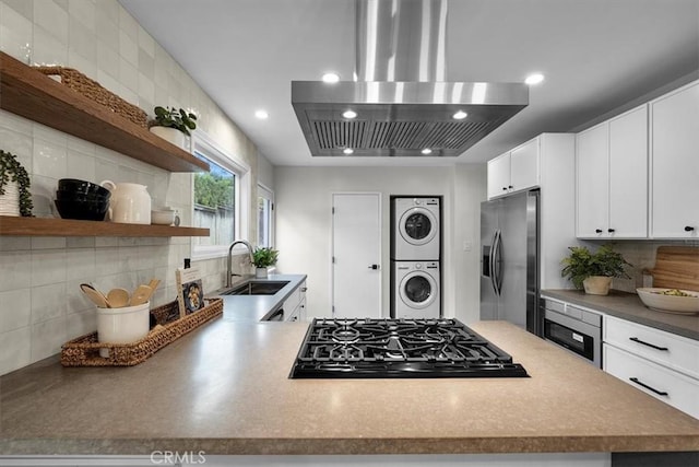 kitchen featuring sink, stacked washing maching and dryer, stainless steel refrigerator with ice dispenser, white cabinets, and island exhaust hood