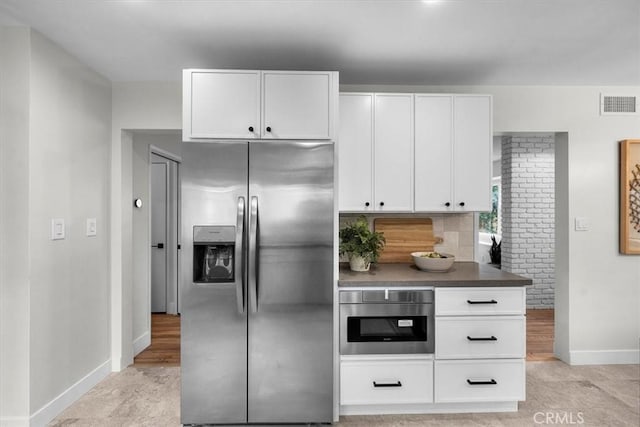 kitchen featuring decorative backsplash, white cabinets, and appliances with stainless steel finishes