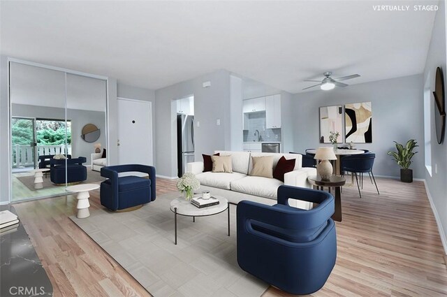 living room featuring ceiling fan, sink, and light wood-type flooring