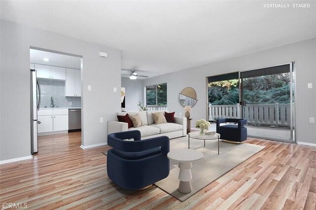 living room featuring ceiling fan, sink, and light hardwood / wood-style floors