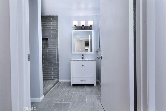 bathroom featuring a tile shower and vanity