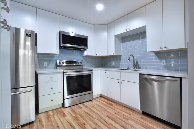 kitchen featuring white cabinetry, stainless steel appliances, sink, and backsplash