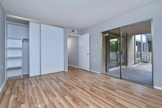 unfurnished bedroom featuring access to exterior, light hardwood / wood-style floors, and a textured ceiling