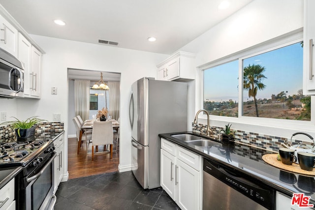 kitchen featuring sink, backsplash, stainless steel appliances, white cabinets, and decorative light fixtures