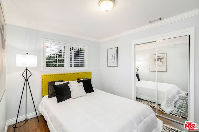 bedroom featuring dark wood-type flooring, ornamental molding, and a closet