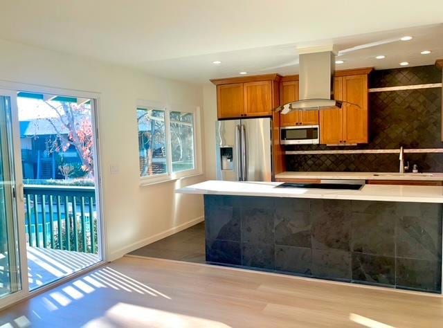 kitchen with sink, backsplash, stainless steel appliances, light hardwood / wood-style floors, and island exhaust hood