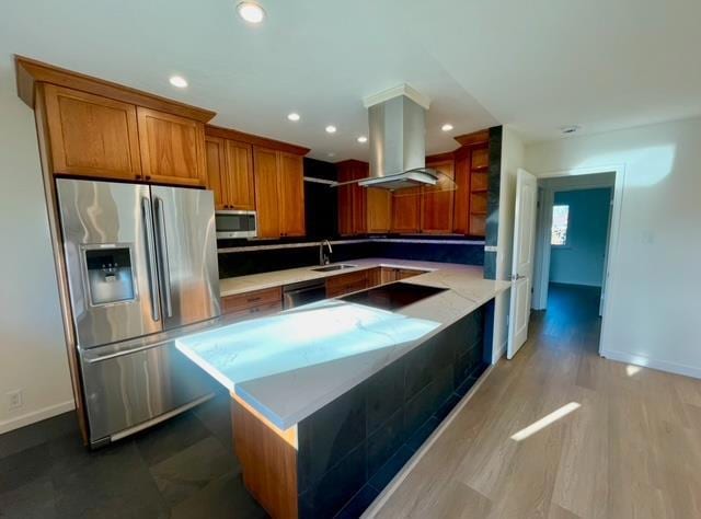 kitchen featuring sink, appliances with stainless steel finishes, kitchen peninsula, island exhaust hood, and light hardwood / wood-style floors