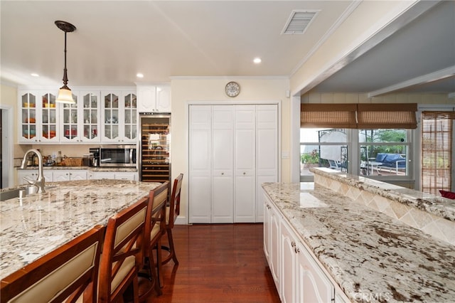 kitchen featuring dark hardwood / wood-style floors, decorative light fixtures, sink, white cabinets, and ornamental molding