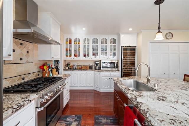 kitchen featuring wine cooler, wall chimney exhaust hood, sink, appliances with stainless steel finishes, and white cabinets