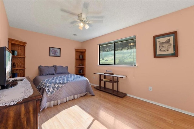 bedroom with a textured ceiling, light hardwood / wood-style floors, and ceiling fan