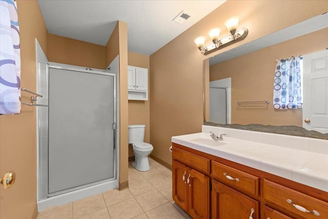 bathroom featuring tile patterned flooring, vanity, toilet, and a shower with shower door