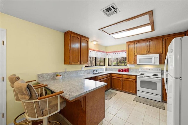 kitchen with sink, a breakfast bar area, light tile patterned floors, kitchen peninsula, and white appliances