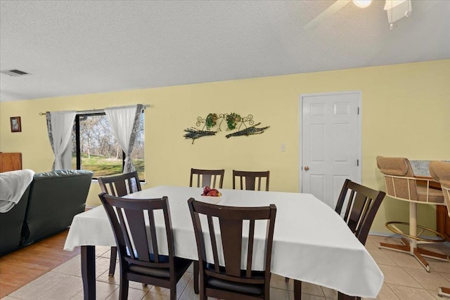 tiled dining space with ceiling fan and a textured ceiling