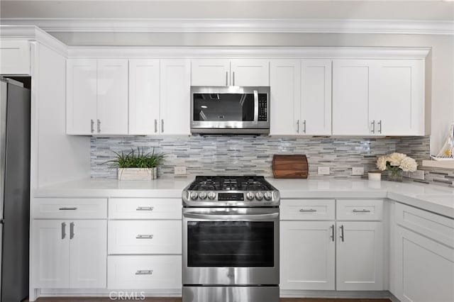 kitchen with white cabinetry, ornamental molding, appliances with stainless steel finishes, and tasteful backsplash