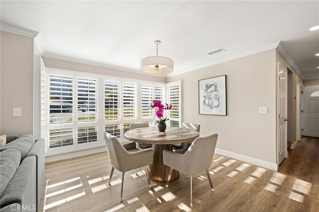 dining space featuring hardwood / wood-style flooring and crown molding