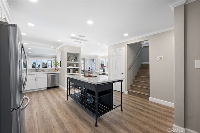 kitchen with light wood-type flooring, stainless steel appliances, white cabinets, and a kitchen island