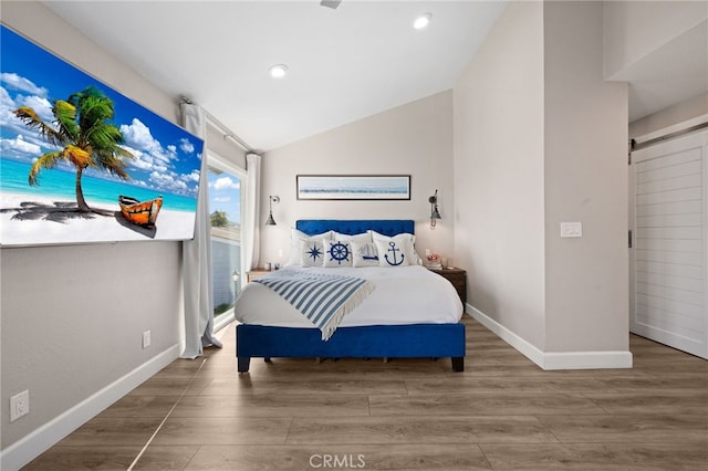 bedroom with lofted ceiling, hardwood / wood-style floors, and a barn door